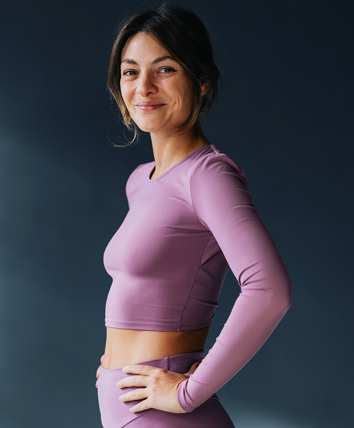 Smiling woman in purple workout attire.