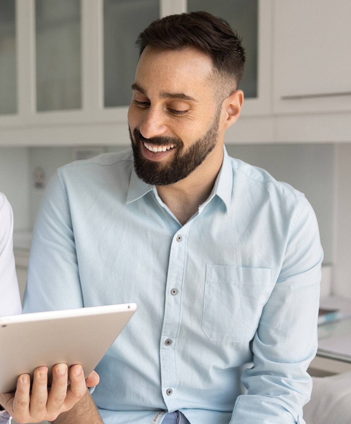 Man smiling while using a tablet computer.