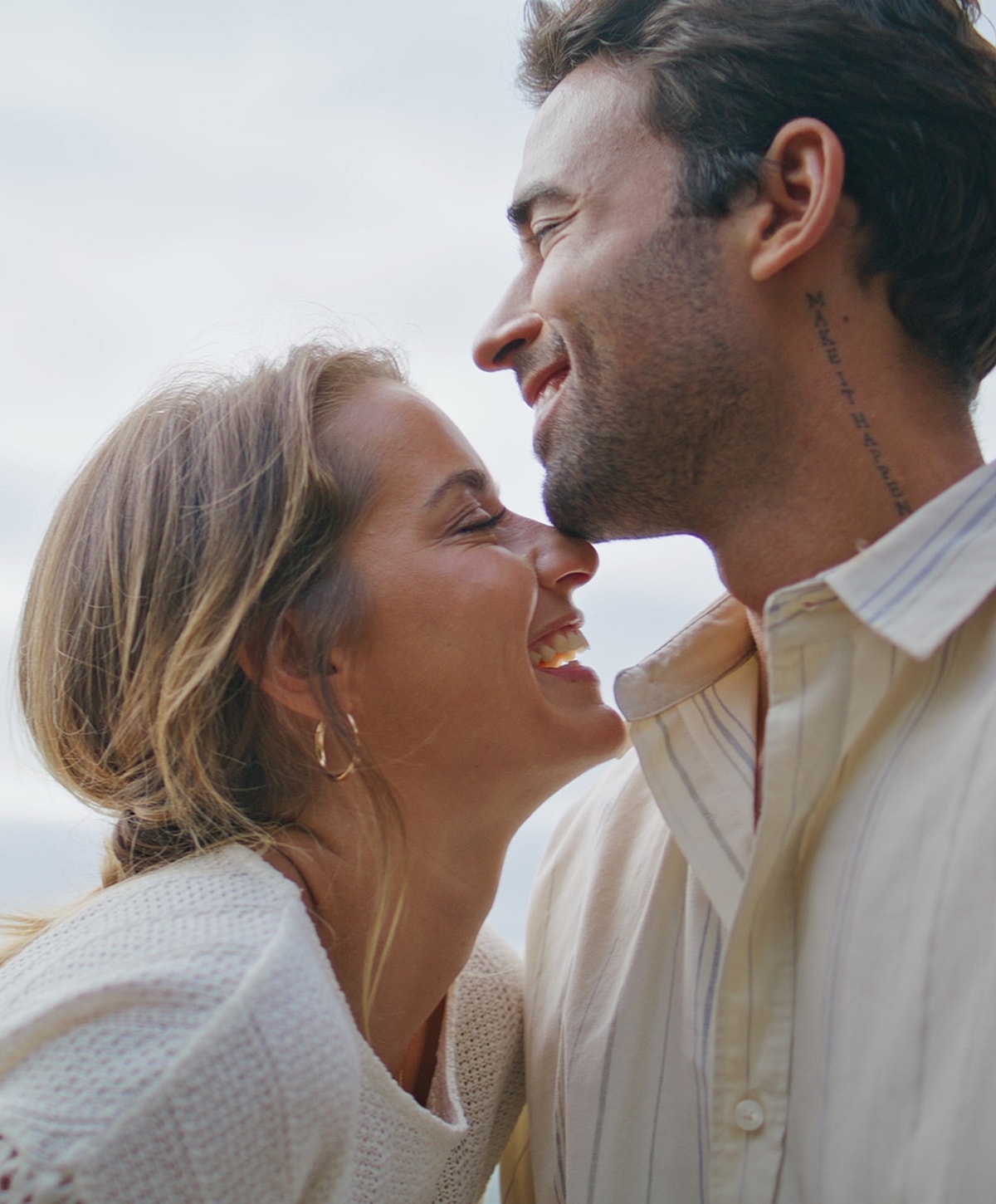 Couple smiling joyfully close together outdoors.