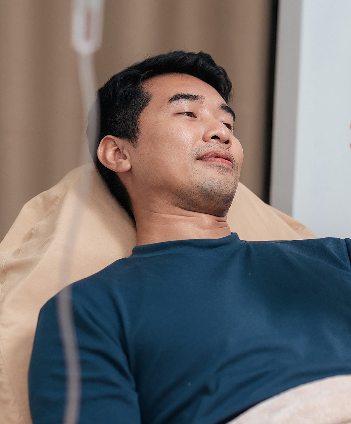 Man resting in hospital bed with IV drip.
