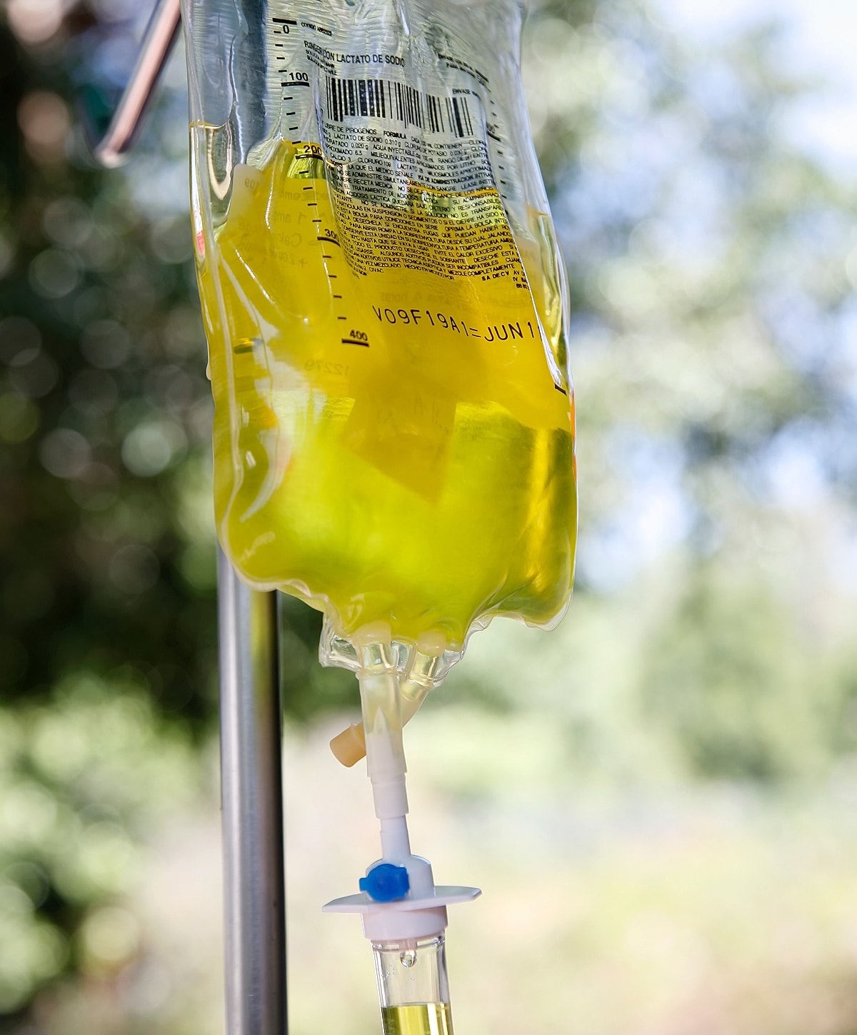 IV bag with yellow liquid hanging outdoors