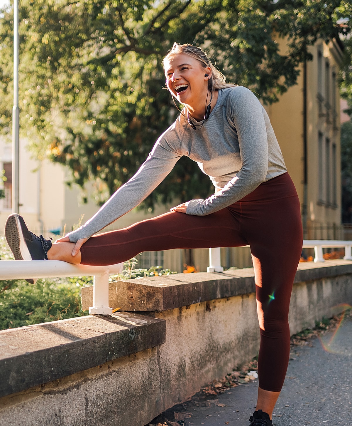 Woman stretching outdoors while smiling happily.
