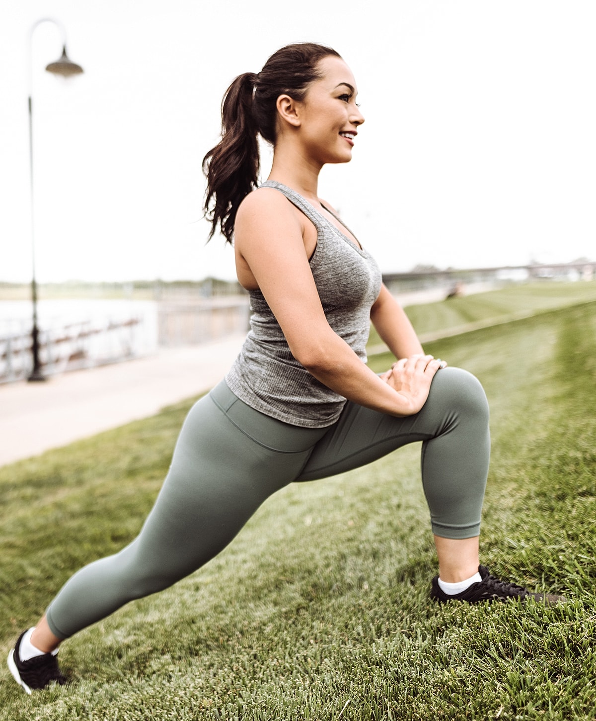 Woman stretching outdoors on grassy field.