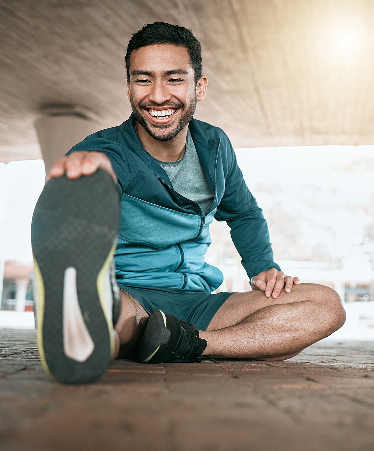 Man stretching and smiling outdoors in activewear.