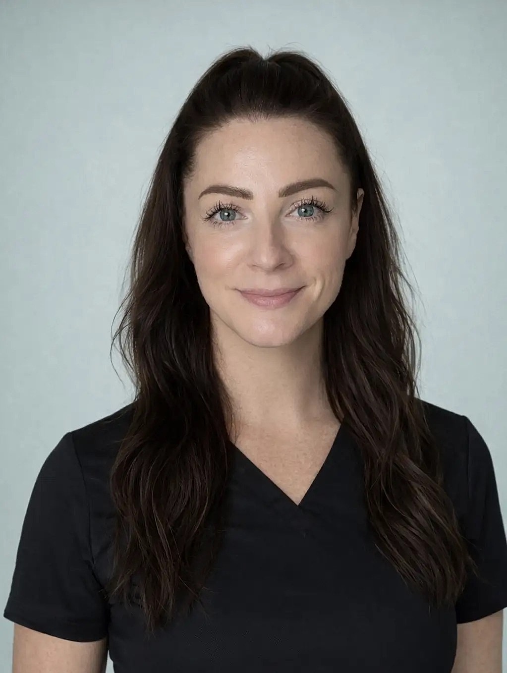 Smiling woman in black medical scrubs, neutral background