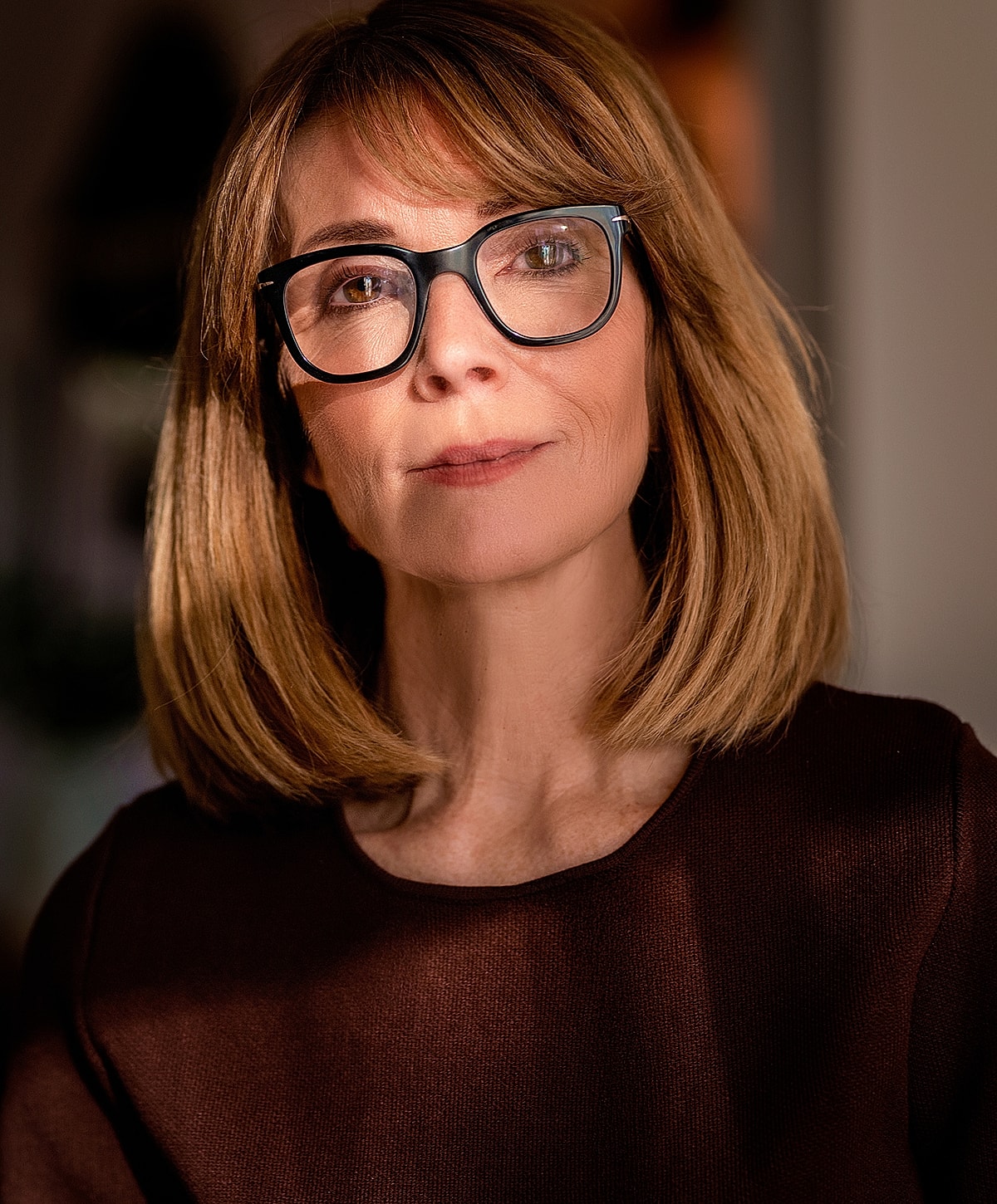 Woman with glasses in soft lighting portrait.